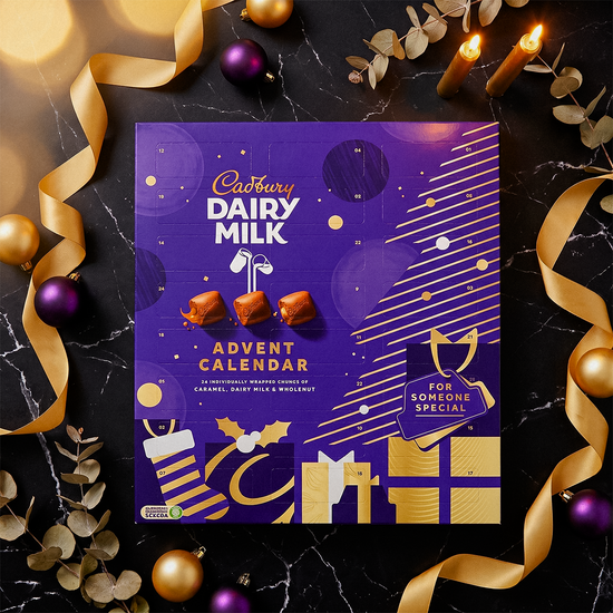 Cadbury Dairy Milk advent calendar on a dark surface with gold ribbons, baubles, and festive lights