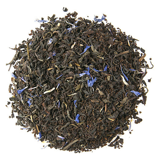 Black and dark green tea leaves with blue flowers on a white background
