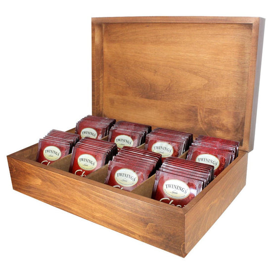 A wooden tea chest with multiple compartments, each filled with red Twinings Chai tea bags.
