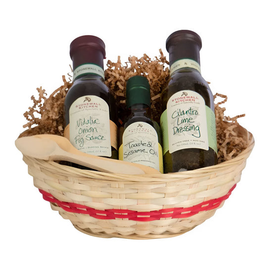 Three bottles of Stonewall Kitchen dressings in a woven basket with red trim on a white background.