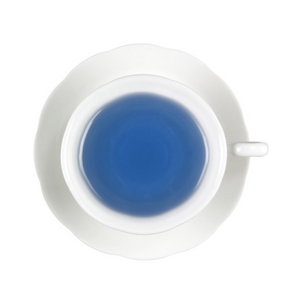 White ceramic teacup with blue liquid hot tea on a white background