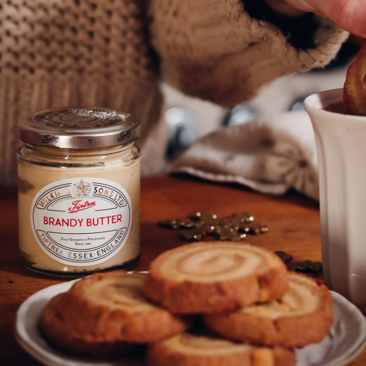 Brandy butter jar with a plate of cookie and mug of tea.