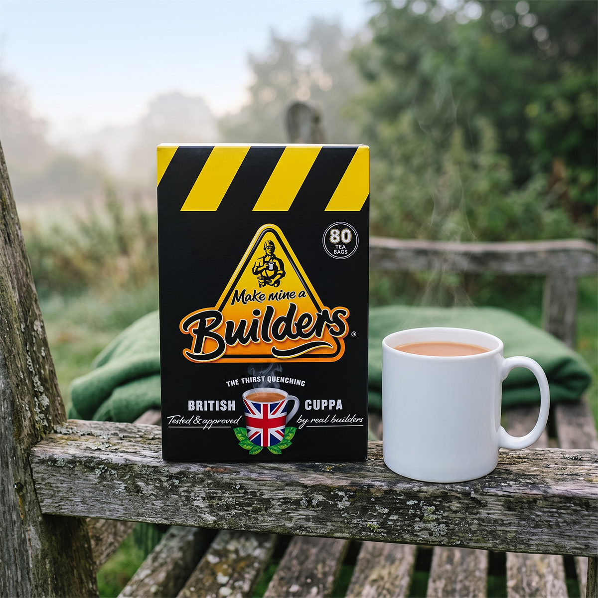 Builder's tea box and a white mug on a wooden ledge with a blurred green outdoor background
