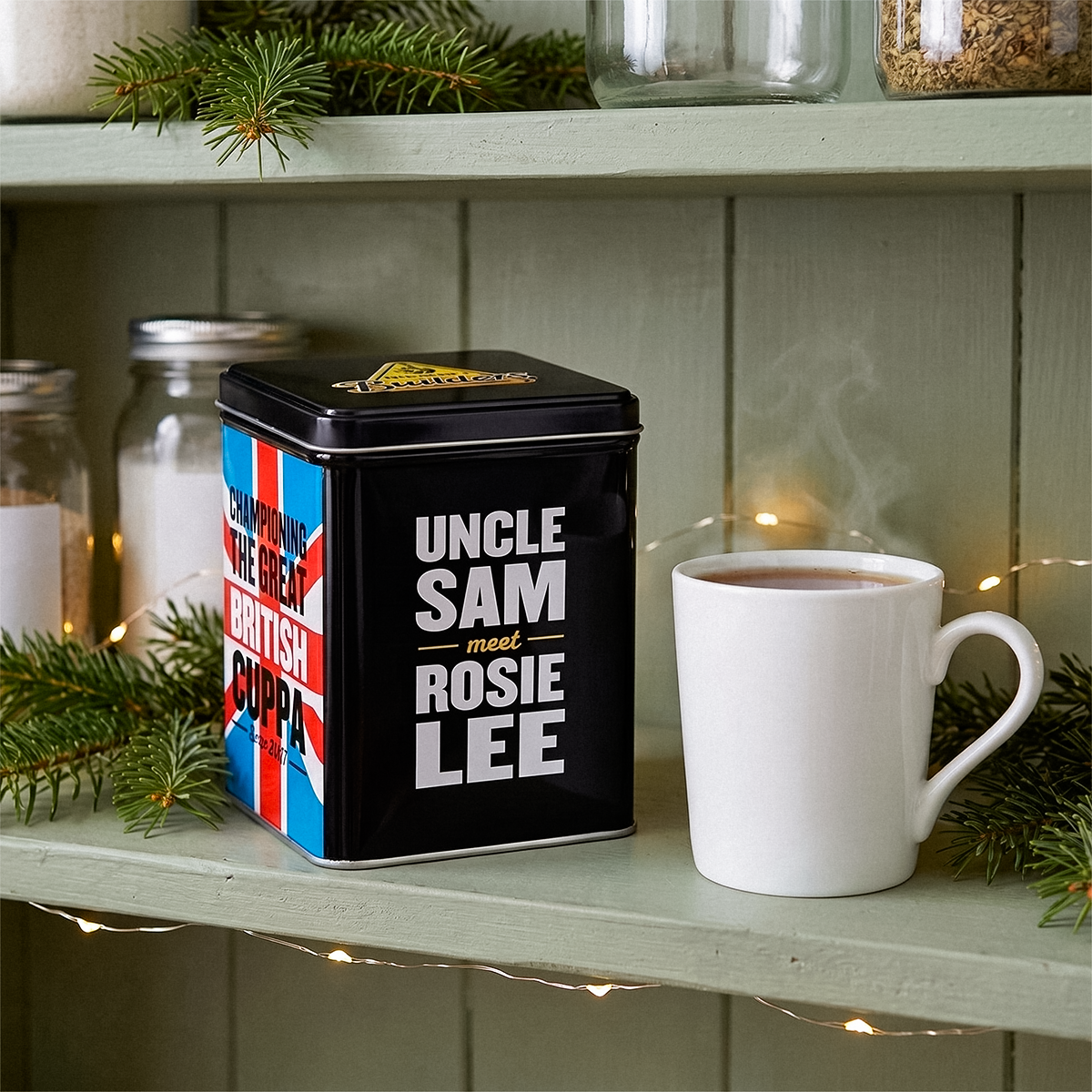 Uncle Sam Rosie Lee tea tin on a shelf with a mug and jars, with pine sprigs