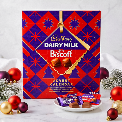 Cadbury Dairy Milk Biscoff Advent Calendar on a white surface with baubles and a plate of chocolates