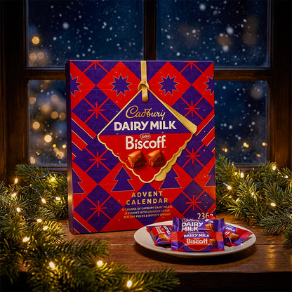 Cadbury Dairy Milk Biscoff Advent Calendar on a table with a snowy window and fairy lights behind