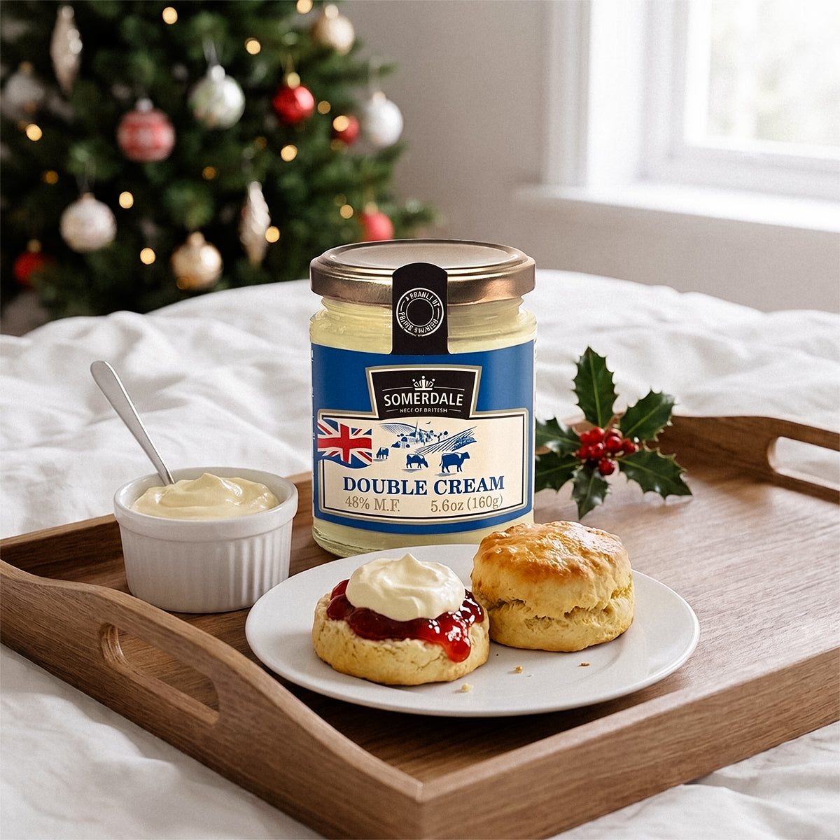Jar and bowl of cream with scones on a wooden tray, Christmas tree and snowy window behind