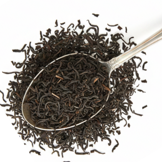 Dark loose-leaf tea leaves piled in a silver spoon on a white background.