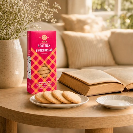 Pink and red patterned product box on a table with scones and a teacup, in a cozy room
