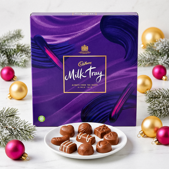 Purple Milk Tray box with a plate of chocolates, baubles, and pine sprigs on a white surface