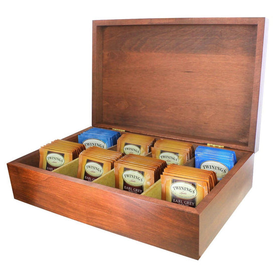 A solid wood tea chest in black, opened to display rows of individually wrapped Twinings tea bags, arranged by flavor.