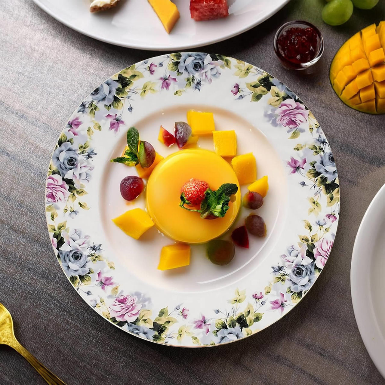 Yellow dessert with fruit on a floral plate on a gray surface