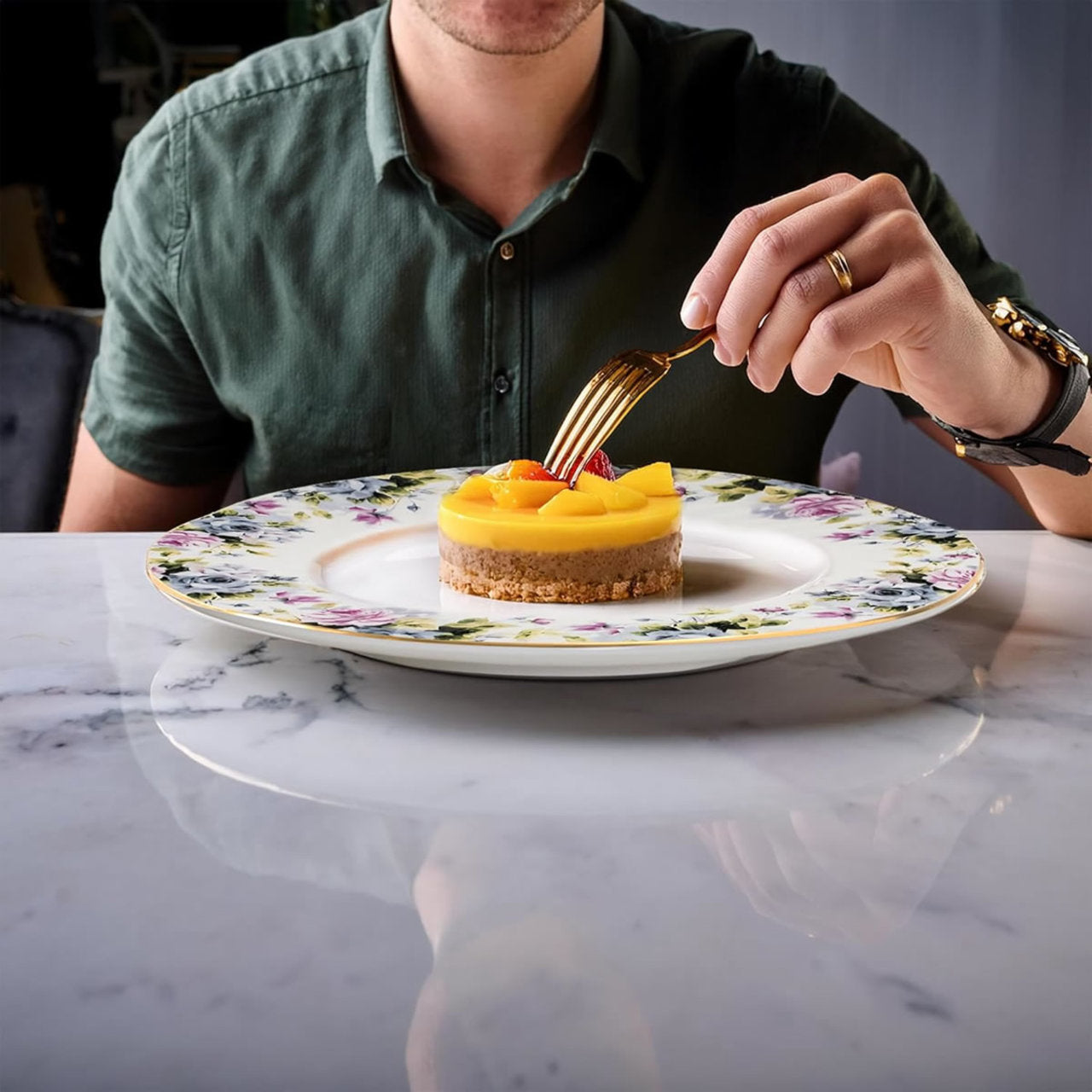 Person about to eat a dessert on a floral plate with a marble table.