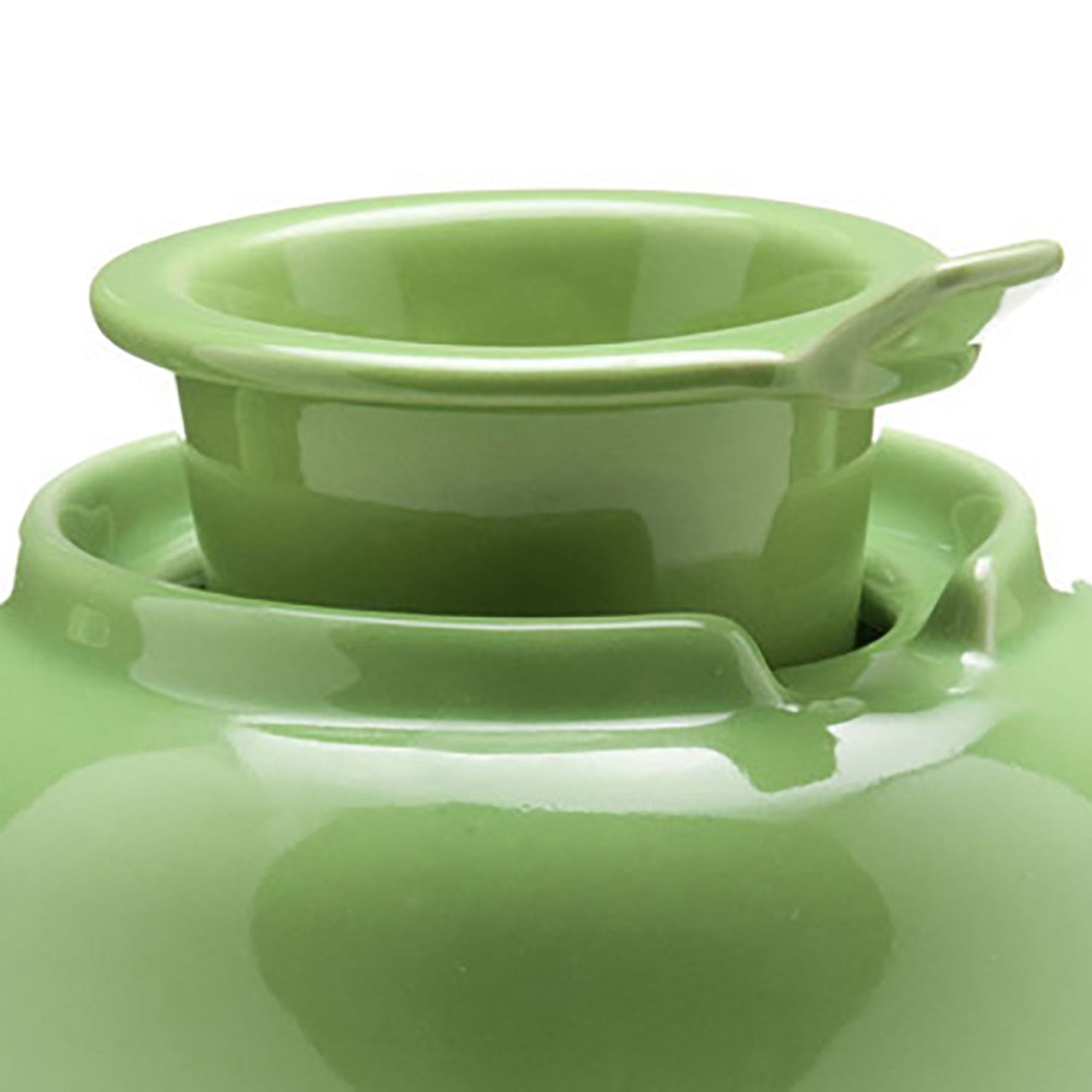 Green ceramic teapot with infuser sticking out the top on a white background