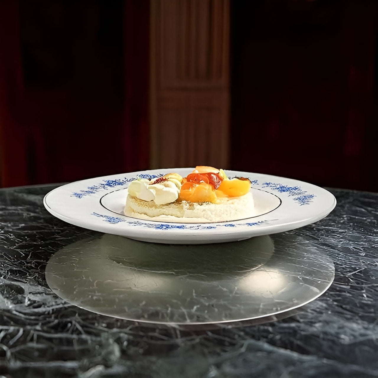 Decorative plate with a fruit topped dessert on a dark surface
