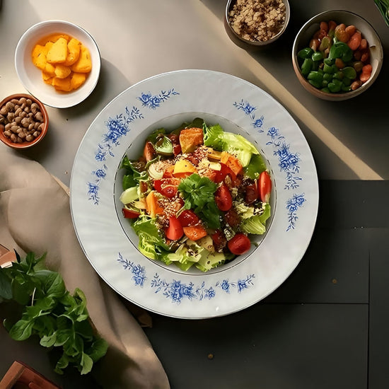 Assorted salad on a decorative plate with side dishes on a table.