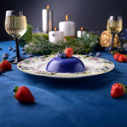 Blue dessert on a floral plate with candles and glasses in the background