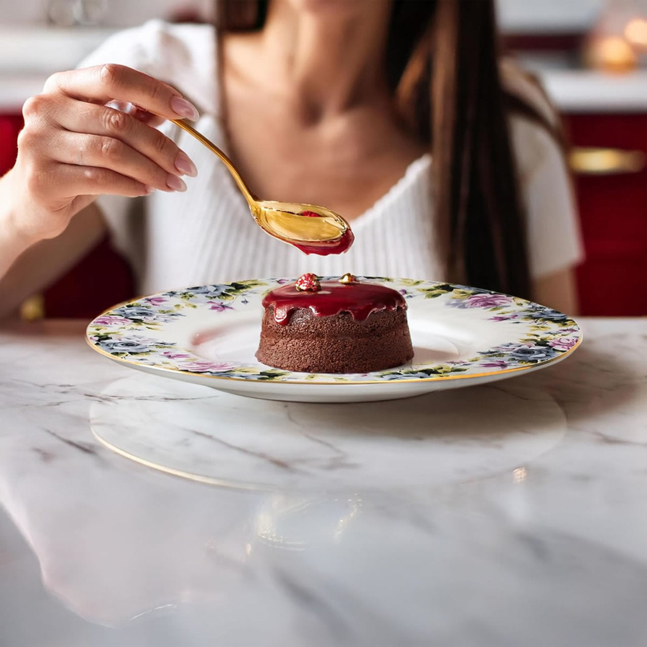 Person drizzling syrup over a dessert on a floral plate