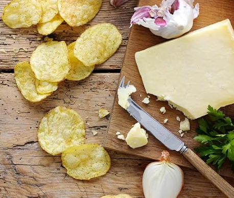 potato chips next to cheese and onions on a cutting board.