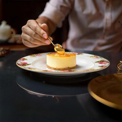 Person drizzling syrup over a small cake on a decorative plate.