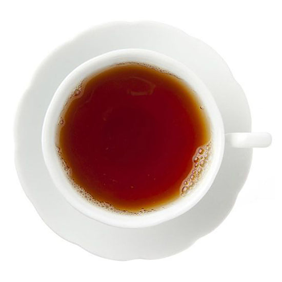 White cup and saucer with a dark amber hot tea on a white background