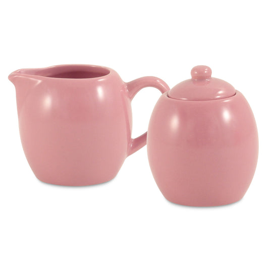 Pink ceramic creamer and sugar bowl set on a white background