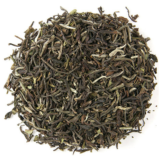 Top down view of dry green tea leaves in a circle pattern on a white background