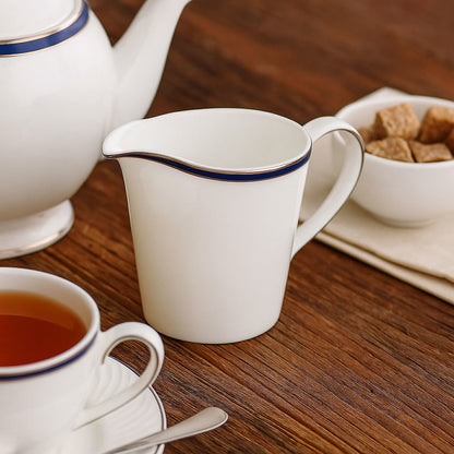 Tea set with teapot, cup, and creamer on a wooden table.